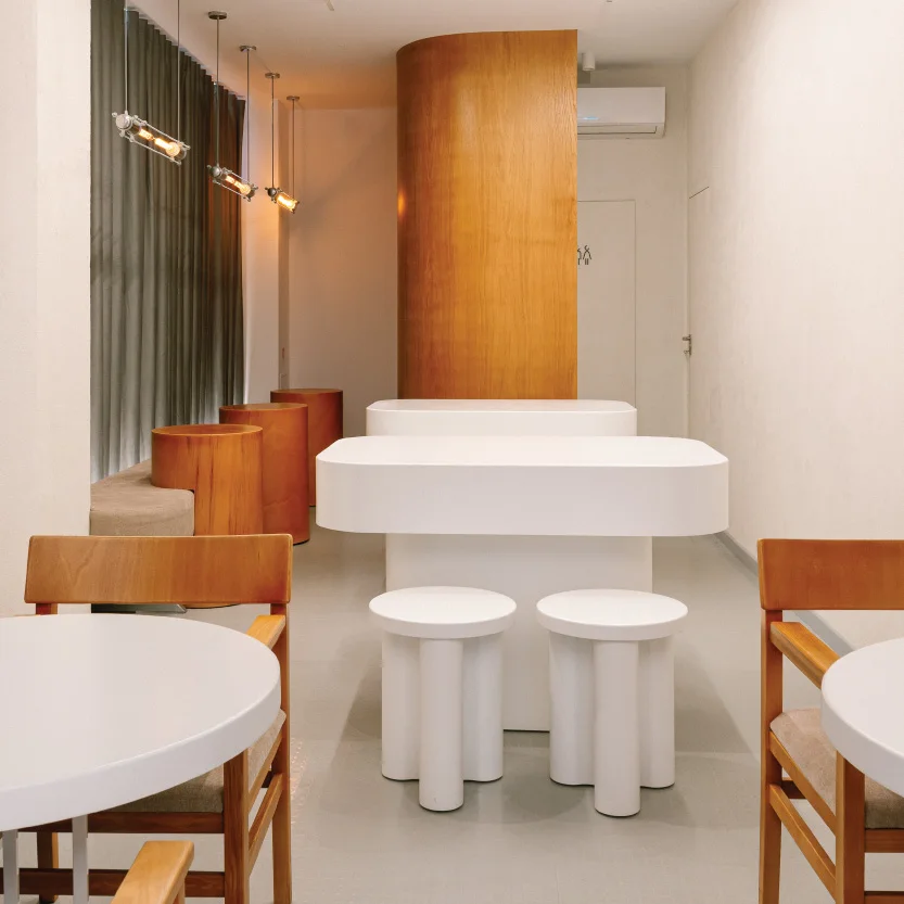 Interior de cafenea minimalistă, cu linii curate, lemn deschis și multă lumină naturală